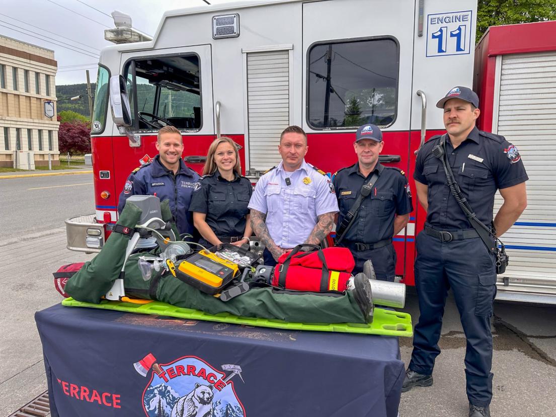 several emergency responders pose with the LUCAS CPR device outside with a fire engine behind them